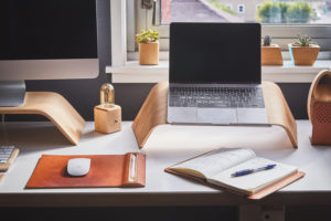 desk setup with iMac, laptop, and notebook